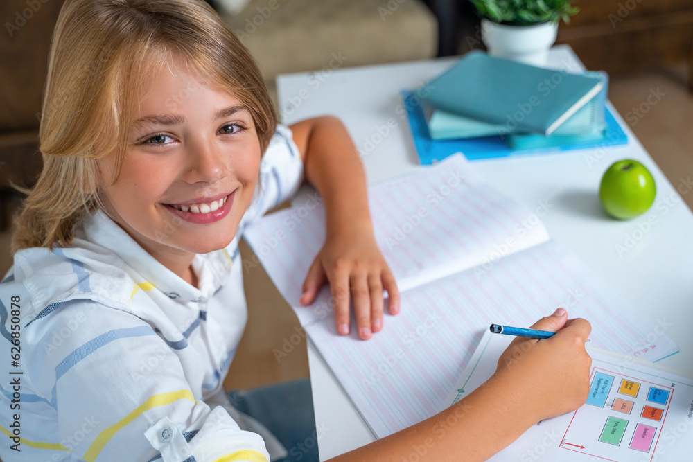 Primary school smiling boy girl sitting at desk, studying alphabet writing letter book and tablet at class home looking at camera. Copy space for advertising blank concept. Back to school. Education