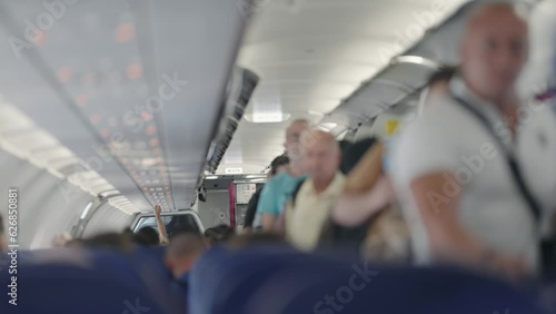 Passenger boarding on plane and putting luggage on overhead locker compartment shelf in an airplane. Trip concept, slow motion