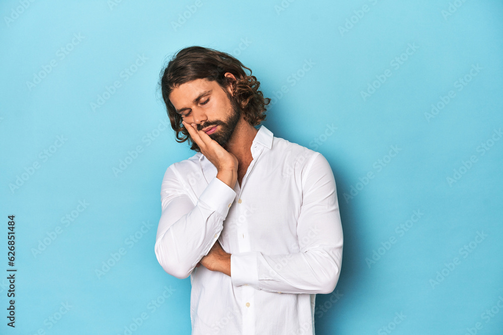 Bearded man in a white shirt, blue backdrop who is bored, fatigued and need a relax day. Bearded man in a white shirt, blue backdrop who is bored, fatigued and need a relax day.