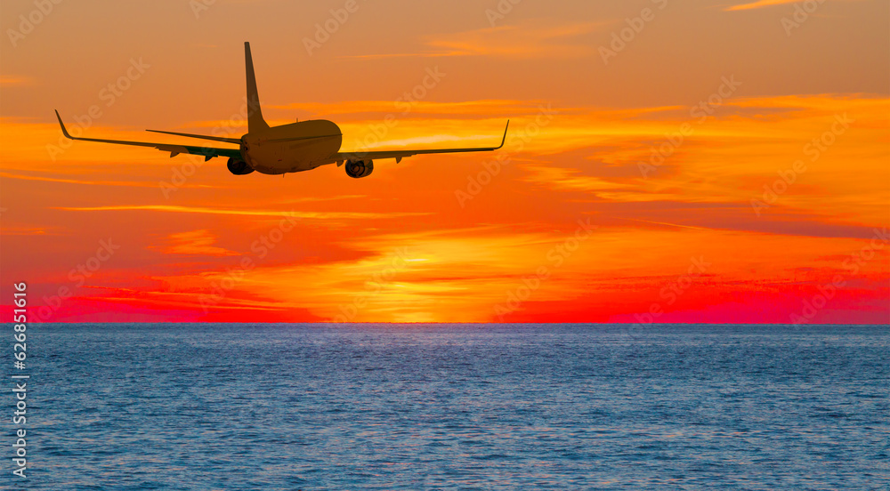 Airplane in the sky flying over tropical sea at sunset Airplane in the sky flying over tropical sea at sunset