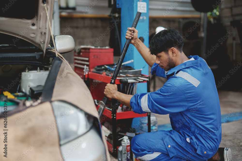 Asian auto mechanic changing tires. Asia Man picks up a car jack to change a tire. Asian auto mechanic changing tires. Asia Man picks up a car jack to change a tire.