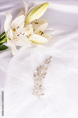 Beautiful vertical wedding background. A gorgeous comb with rhinestones on the bride's snow-white veil and white live lilies. decor. layout