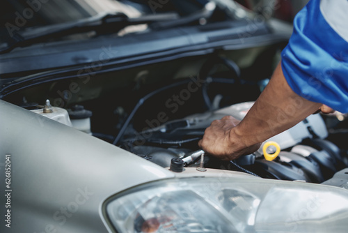 Professional mechanic checking and repairing a car. Auto mechanic working in garage. Repair service.