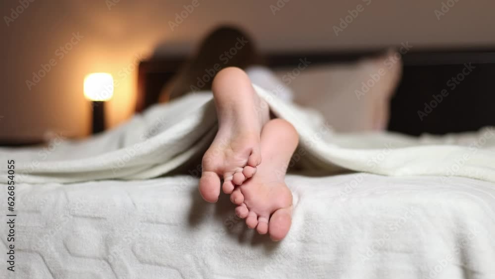 Feet on the bed under a white blanket. Feet on the bed under a white blanket.