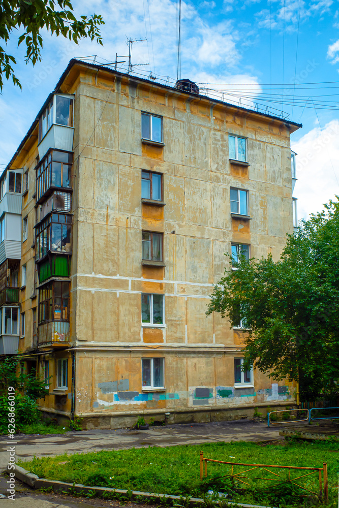 Fragment of the facade of an old five-storey residential building on a summer day