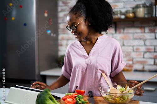 Young woman in kitchen. Beautiful woman making salad.