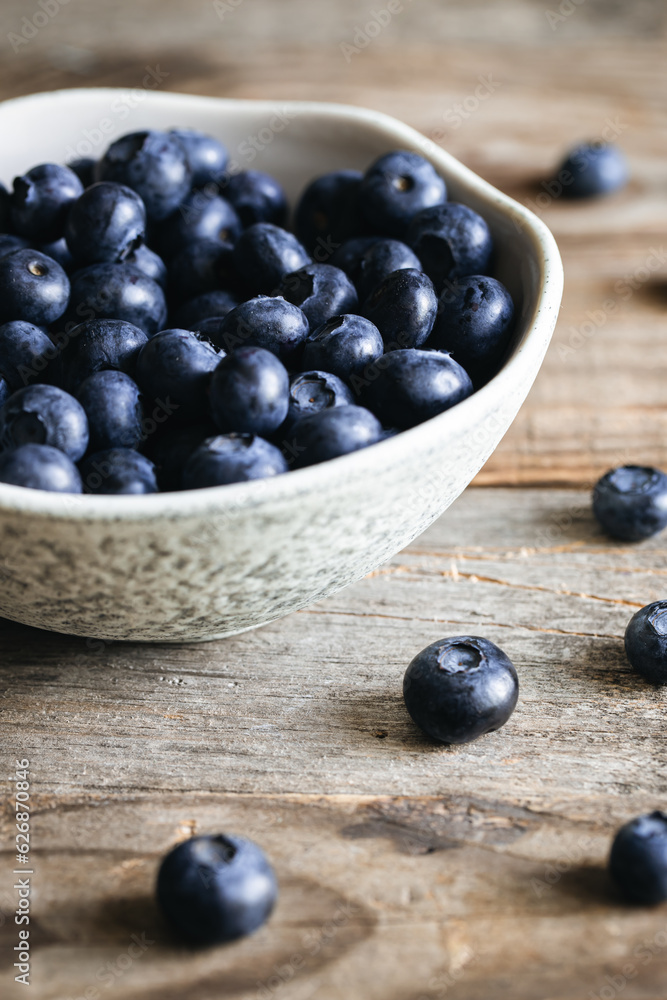 Ceramic white bowl with blueberries on a wooden background, rustic style. Ceramic white bowl with blueberries on a wooden background, rustic style.