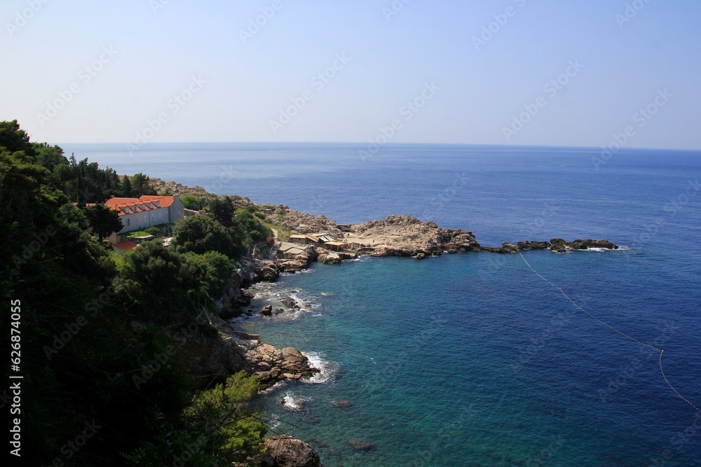 Clear Blue Water Adriatic Sea coastline view with tree, agave, plant and stone in front, Dubrovnik, Croatia Clear Blue Water Adriatic Sea coastline view with tree, agave, plant and stone in front, Dubrovnik, Croatia