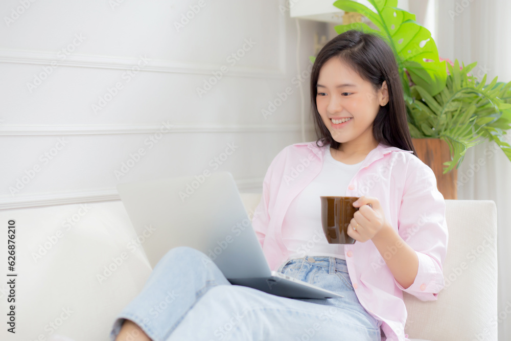Young asian business woman work from home with laptop computer and drinking coffee on sofa in living room, freelance girl using notebook sitting on couch with comfort and relax, lifestyles concept. Young asian business woman work from home with laptop computer and drinking coffee on sofa in living room, freelance girl using notebook sitting on couch with comfort and relax, lifestyles concept.