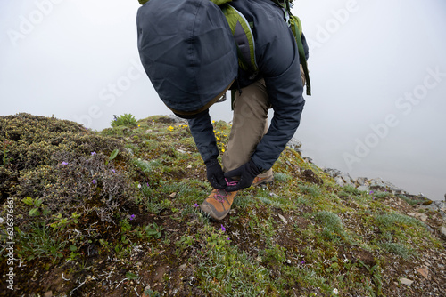 Successful woman hiker tying shoelace at mountain top in tibet