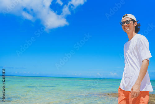 南国の美しいビーチを歩くサングラスをかけた男性