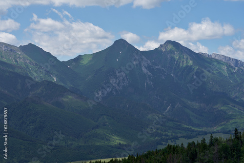 Góry piękne zdjęcie przedstawiające krajobraz górski wysokie szczyty i doliny nad którymi jest niebieskie niebo z kłębiącymi się chmurami. 