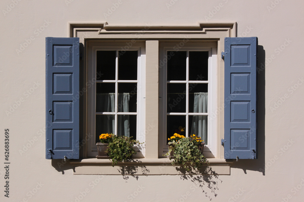 Fototapeta premium White baroque window with flower pot and blue shutters on a residential house in the old village of Neu-Bamberg, Germany
