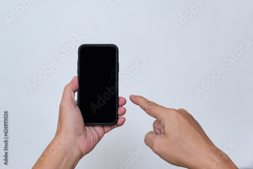 A man's hand pointing at a smartphone in his other hand photo