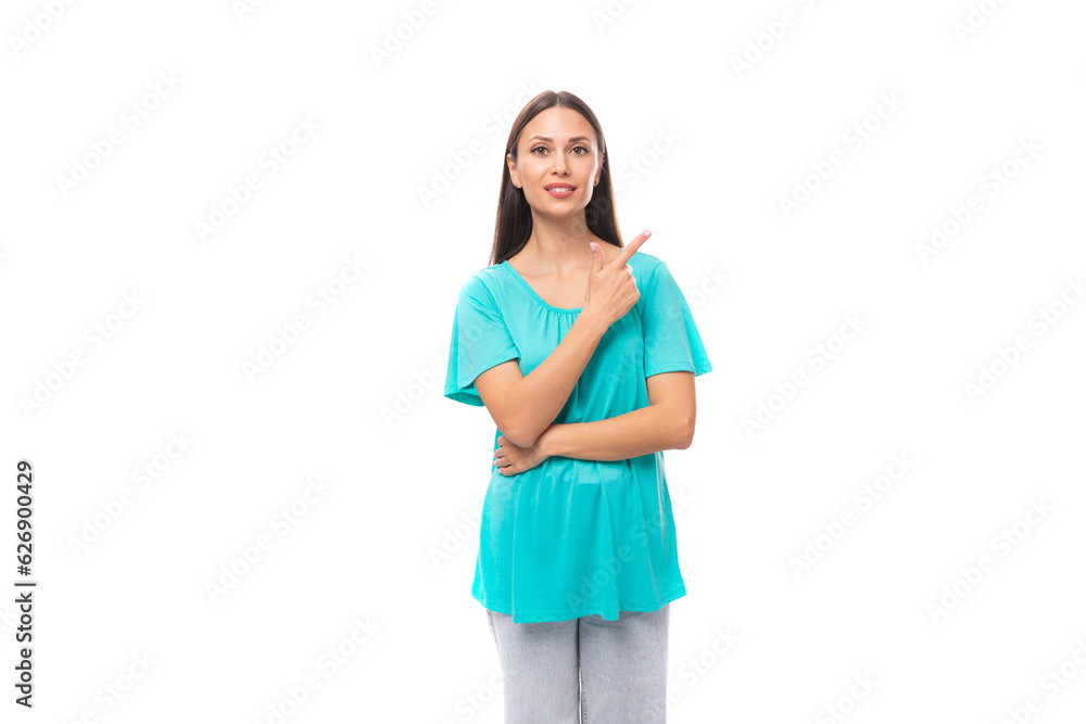 young brunette european lady with straight hair dressed in a blue t-shirt demonstrates with a hand gesture against a wall with advertising space young brunette european lady with straight hair dressed in a blue t-shirt demonstrates with a hand gesture against a wall with advertising space