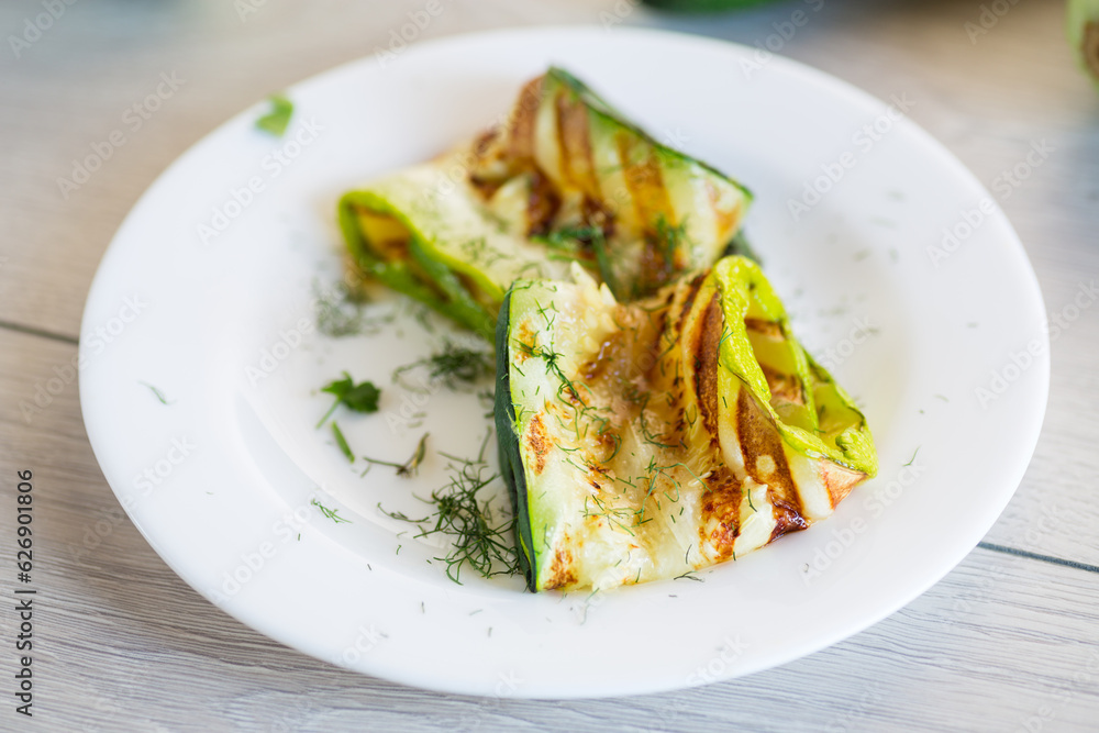 Grilled zucchini pieces with garlic sauce in a white plate.