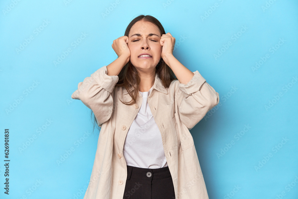 Stylish young woman in an overshirt on a blue background crying, unhappy with something, agony and confusion concept. Stylish young woman in an overshirt on a blue background crying, unhappy with something, agony and confusion concept.