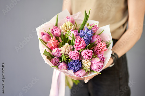Sunny spring morning. Young happy woman holding a beautiful bunch of hyacinths and tulips in her hands. Present for a smiles girl. Flowers bouquet
