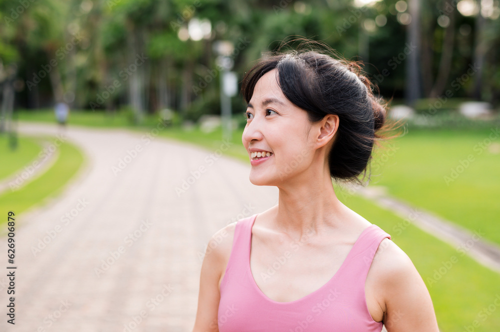 Woman jogger. young asian female happy smile wearing pink sportswear running in public park. Healthcare wellness concept.