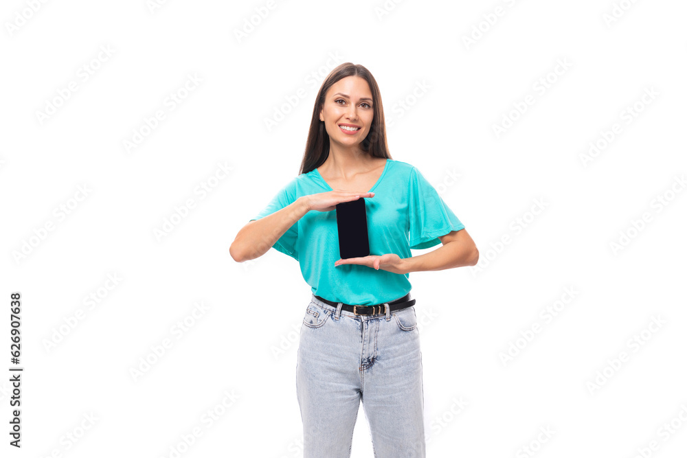 young cute caucasian female model with black silky smooth hair dressed in a blue t-shirt holds a smartphone upright with a mockup for a web page young cute caucasian female model with black silky smooth hair dressed in a blue t-shirt holds a smartphone upright with a mockup for a web page