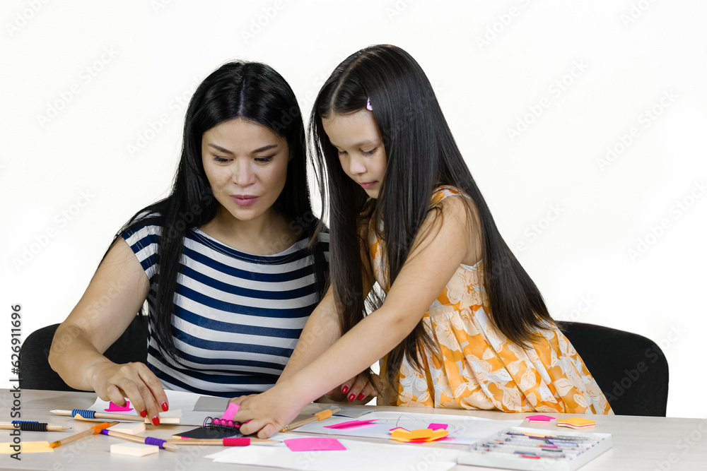 Fototapeta premium Mom and her daughter making handmade paper cutouts and drawing together. Isolated on white.
