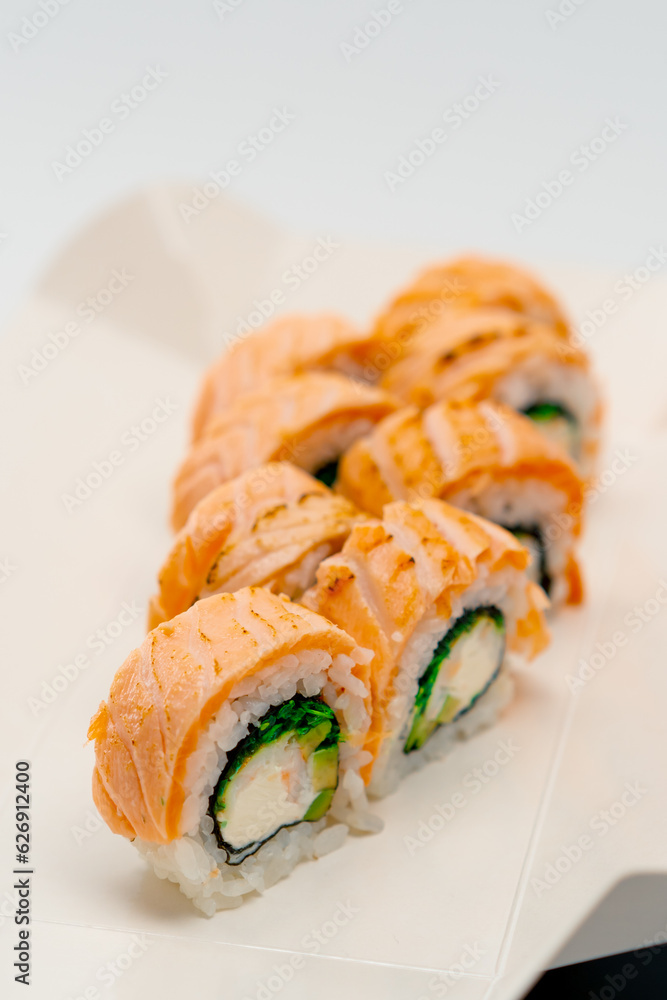 Close-up of a philladelphia roll with salmon cucumber and cottage cheese on a white background in a sushi box 