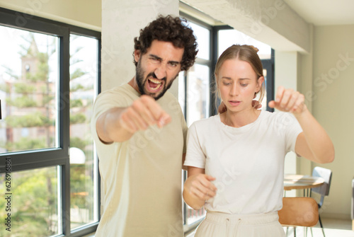 young adult couple looking confident, angry, strong and aggressive, with fists ready to fight in boxing position