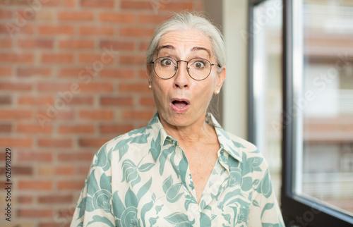 Photos senior pretty woman looking very shocked or surprised, staring with open mouth s