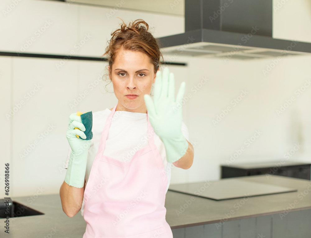 young pretty woman looking serious showing open palm making stop gesture. housekeeper concept young pretty woman looking serious showing open palm making stop gesture. housekeeper concept