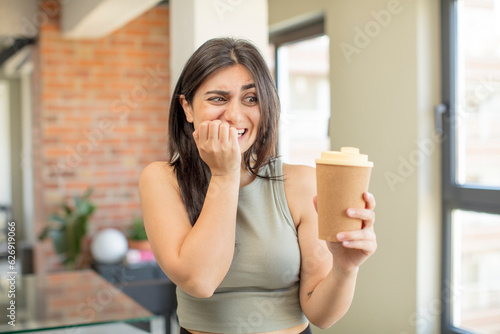 young woman feeling scared, worried or angry and looking to the side. take away coffee