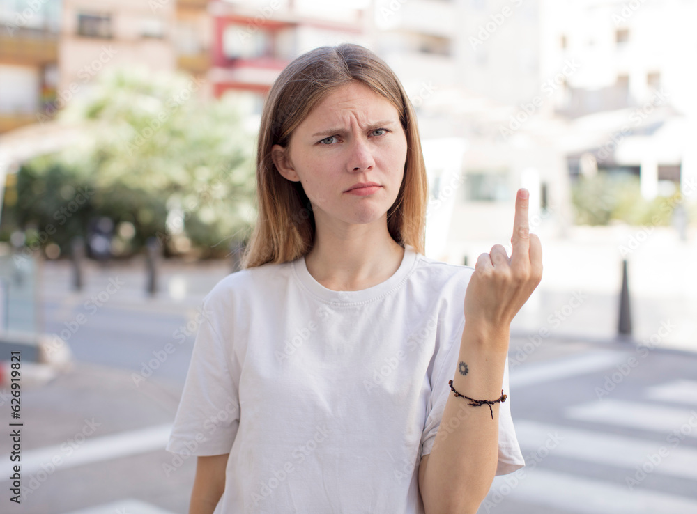 pretty young woman feeling angry, annoyed, rebellious and aggressive, flipping the middle finger, fighting back