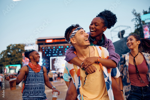 Happy man piggybacking his black girlfriend during open air music concert. photo