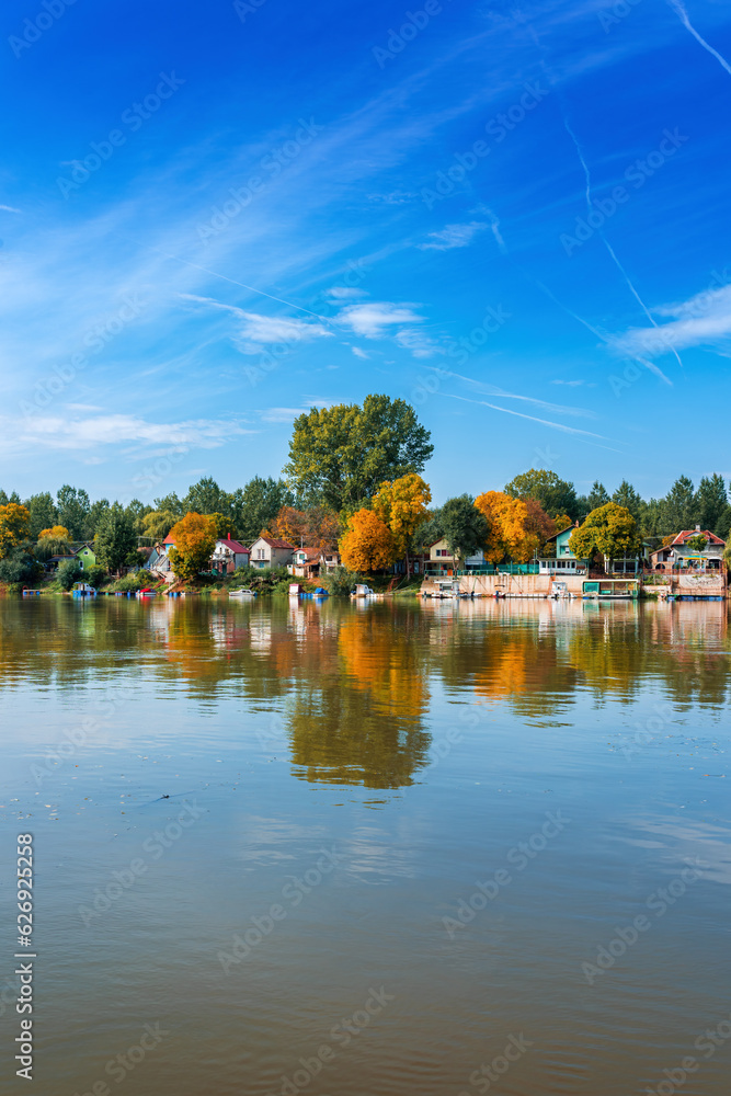 River Tisza and tiny houses at its riverbank in autumn. Beautiful seasonal landscape from Vojvodina, Serbia.