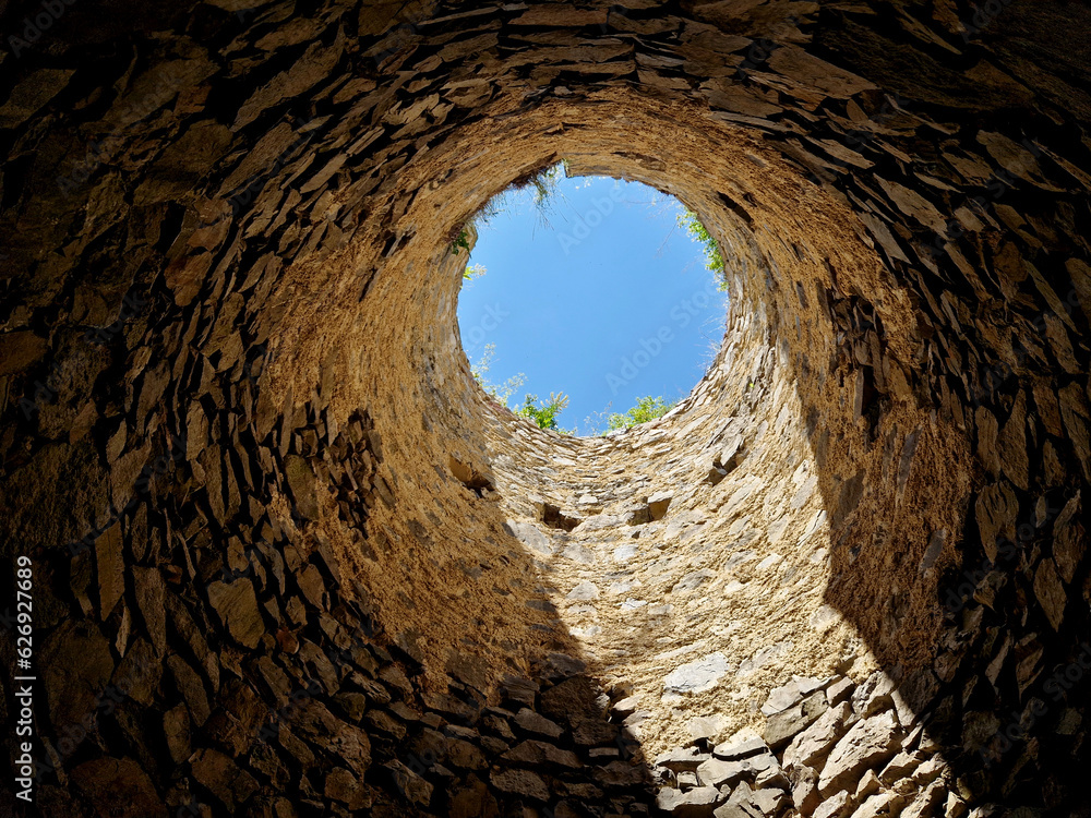 Obraz premium tourists at the old castle fell into the famine. the view from the well up to the light from heaven. the fortress from the Middle Ages needs to be repaired quickly before tourists are injured. search 