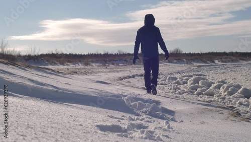 Man Walks in Snow on Remote Frozen Sea Beach on Sunny Winter Day Slow Motion