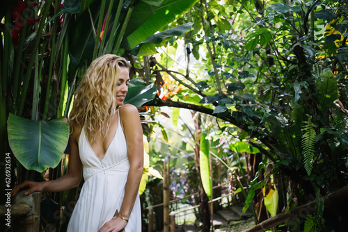 Happy woman in summer dress standing in tropical jungle