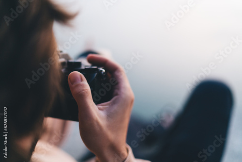 Anonymous man taking photo on camera in blurred nature
