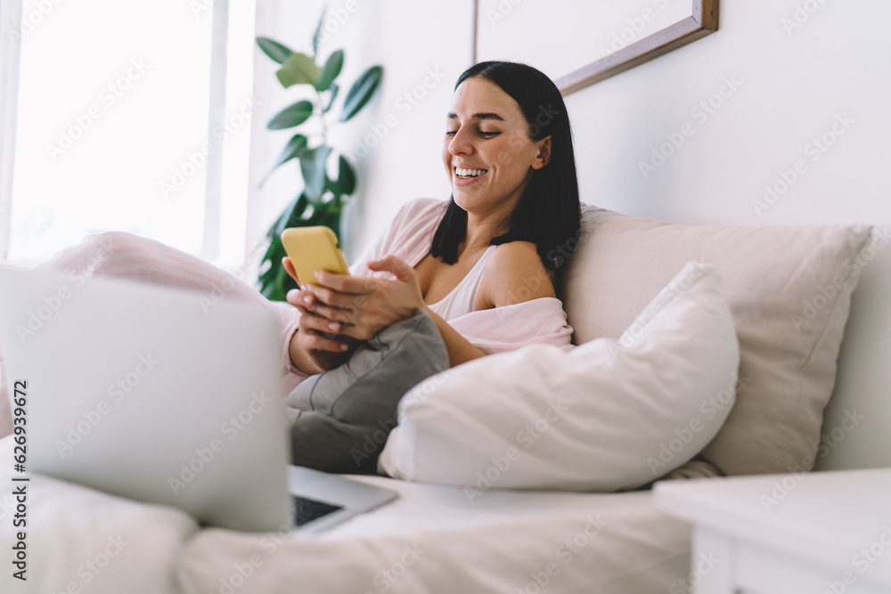 Woman laughing while using smartphone at home Woman laughing while using smartphone at home