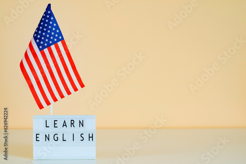 USA flag and text Learn English online on a peach orange wall background. Mockup for presentation banner about online English courses. photo