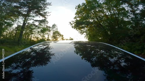 Self driving electric car driving on a country road surrounded by green trees. Green energy concept.