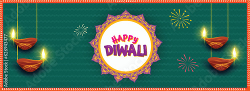 Happy Diwali Celebration Banner or Header Design with Illuminated Oil Lamps (Diya) Hang on Green Fireworks Background.