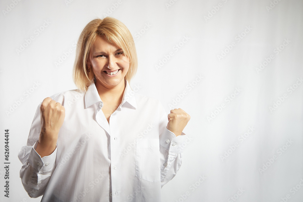 Obraz premium Portrait of a pretty blonde smiling woman posing on a white background. Happy girl model in white shirt in studio. Lady winner is joyfull. Copy space
