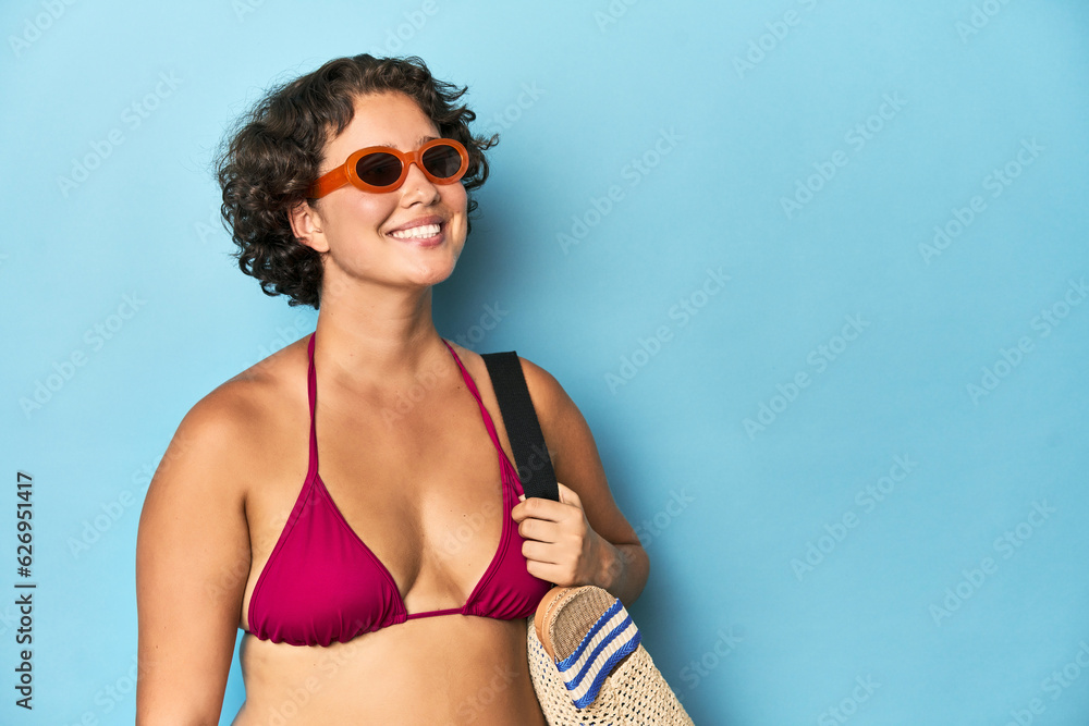 Young Caucasian woman in bikini holding a beach bag, studio shot. Young Caucasian woman in bikini holding a beach bag, studio shot.