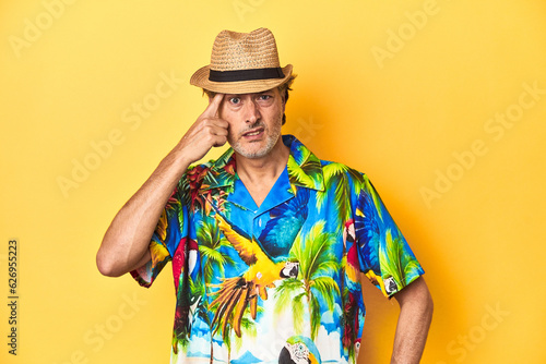 Middle-aged man in Hawaiian shirt and straw hat Middle-aged man in Hawaiian shirt and straw hatshowing a disappointment gesture with forefinger.