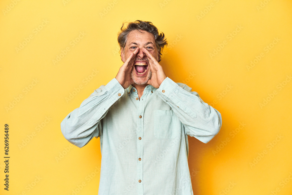 Middle-aged man posing on a yellow backdrop shouting excited to front. Middle-aged man posing on a yellow backdrop shouting excited to front.