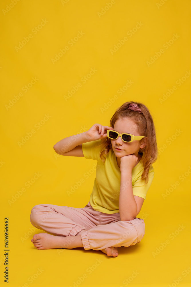 preteen girl in yellow T-shirt sitting floor with empty space isolated yellow color background preteen girl in yellow T-shirt sitting floor with empty space isolated yellow color background