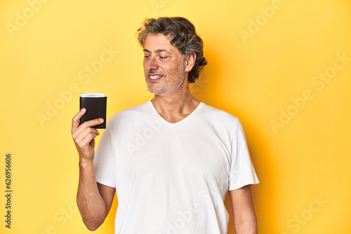 Middle-aged man holding a wallet full of dollars, denoting finance and wealth.