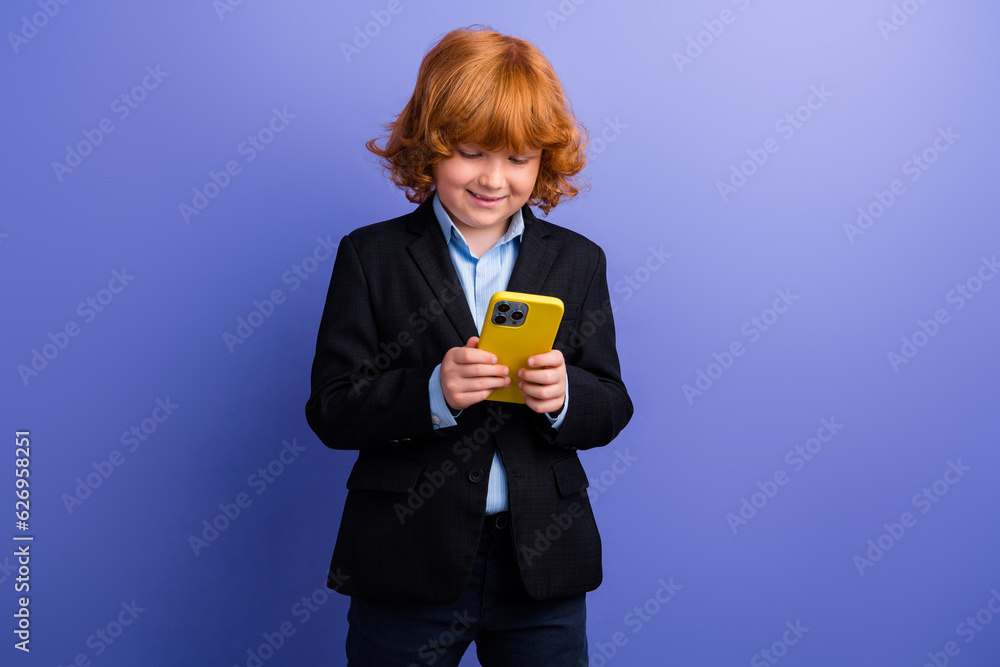 Photo of cheerful satisfied schoolchild use apple iphone gadget texting classmates isolated on violet color background Photo of cheerful satisfied schoolchild use apple iphone gadget texting classmates isolated on violet color background