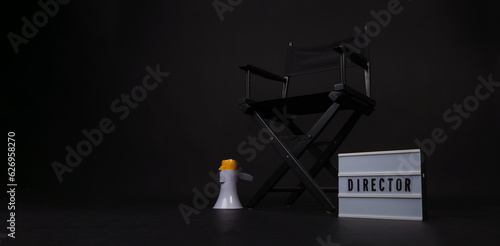Black director chair and clapper board and light box and on black background.