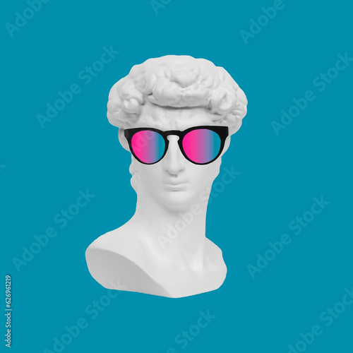 White plaster antique David's statue head in colorful sunglasses isolated on a bright blue color background. 3d trendy collage in magazine style. Contemporary art. Modern creative design